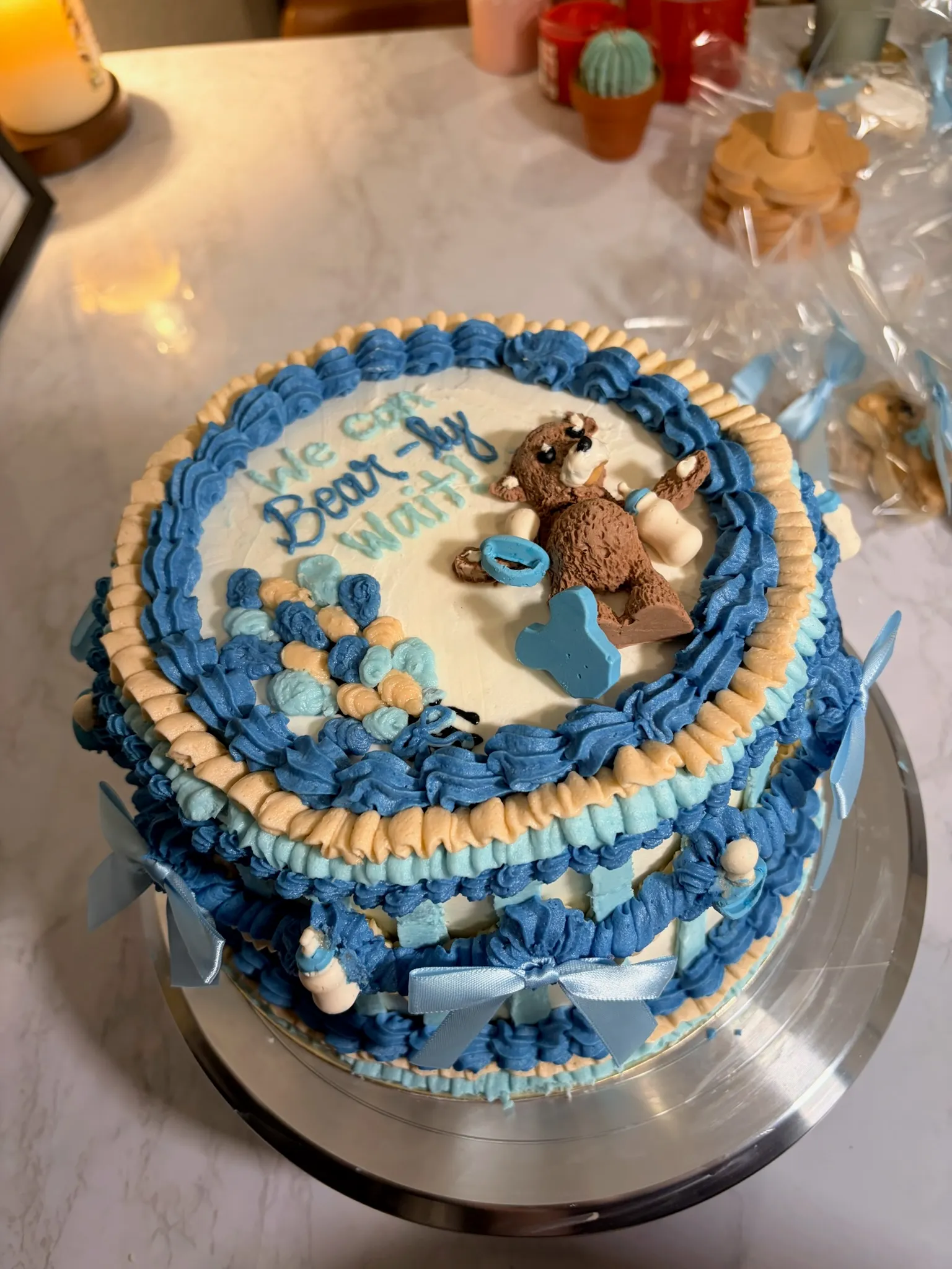 A pale blue vintage cake with ruffled piping and a teddy bear topper