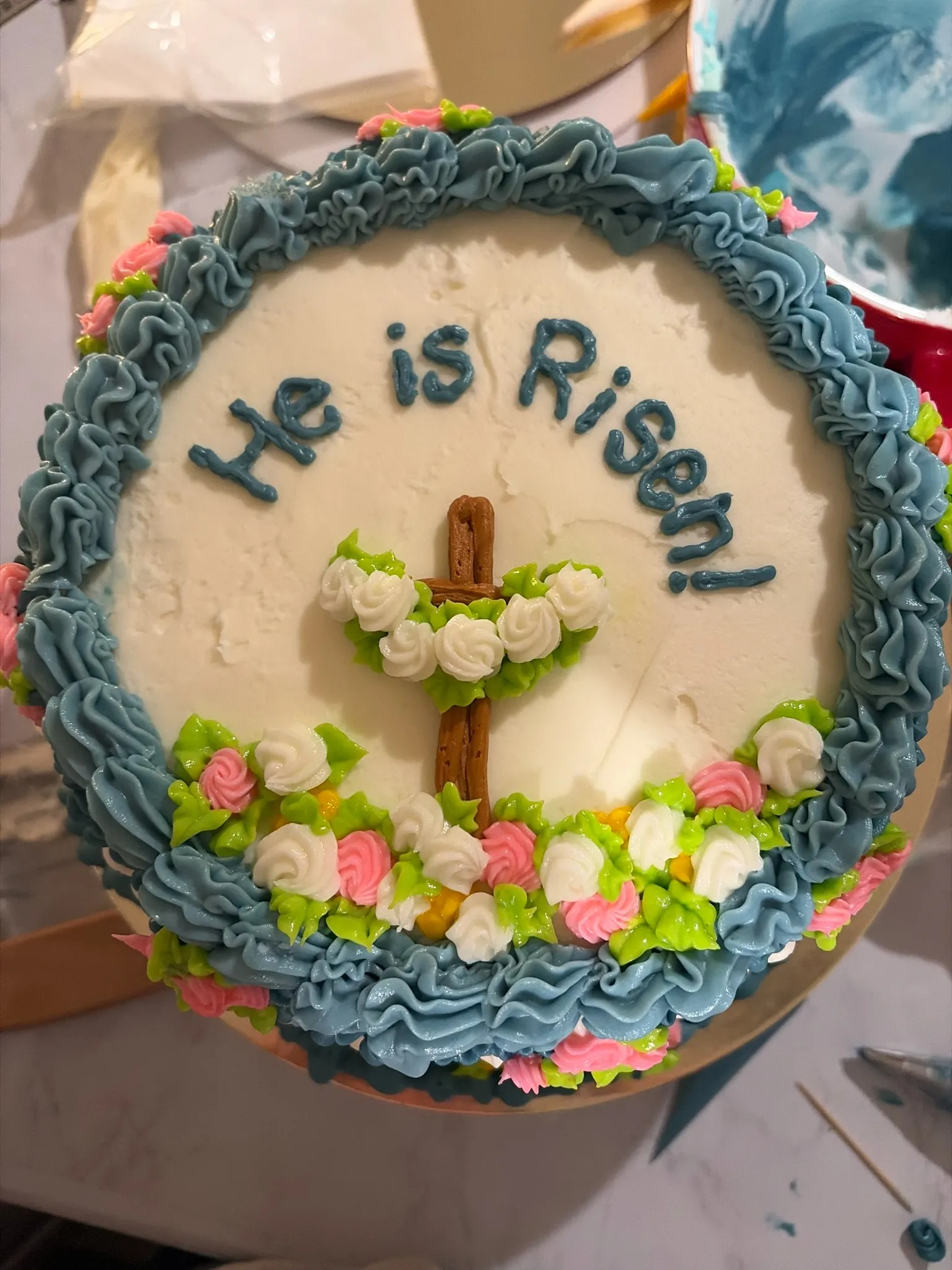 An Easter cake iced 'He is Risen' with a cross and spring flowers