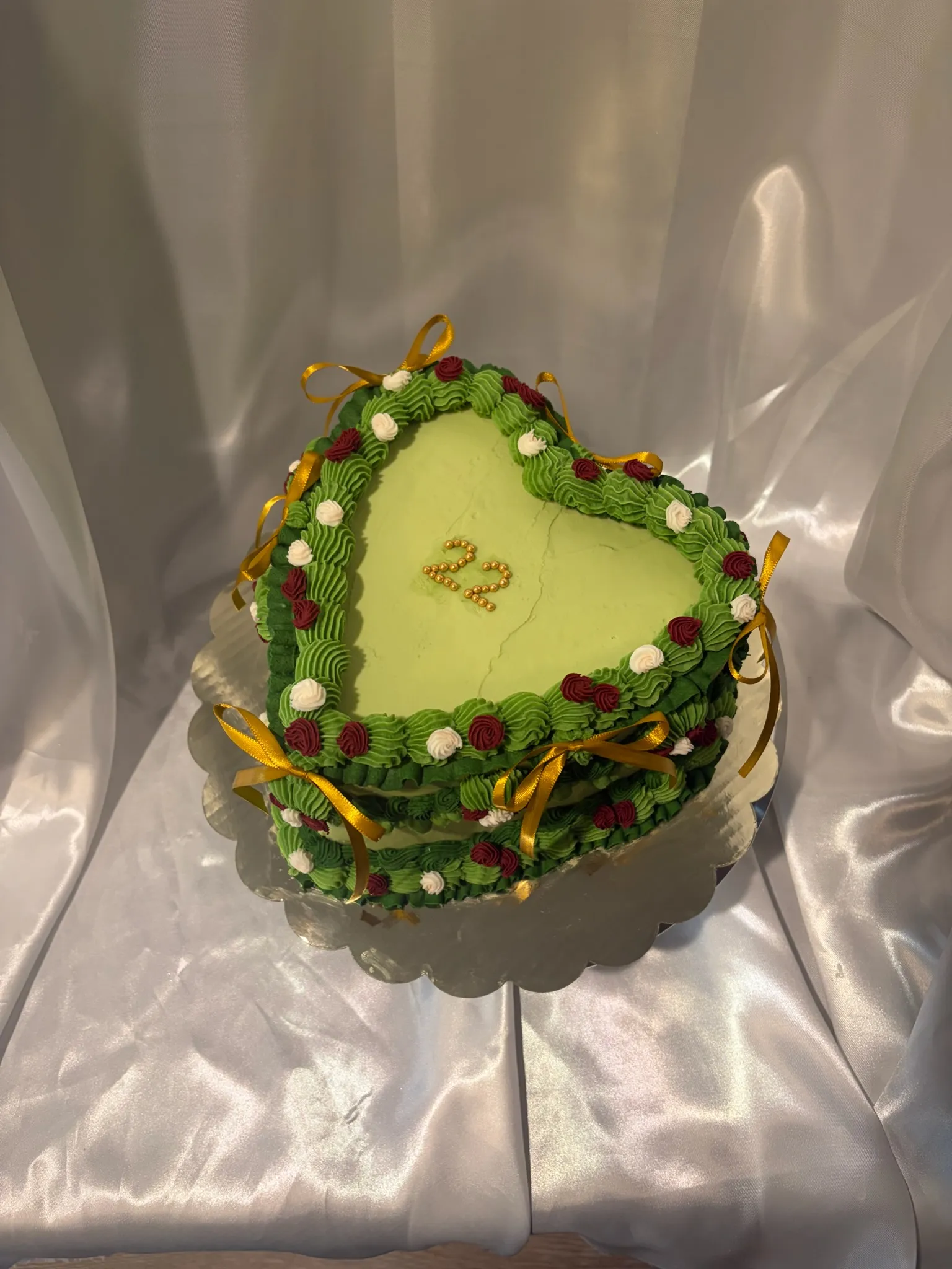 A green heart-shaped cake piped with flowers and the number 22