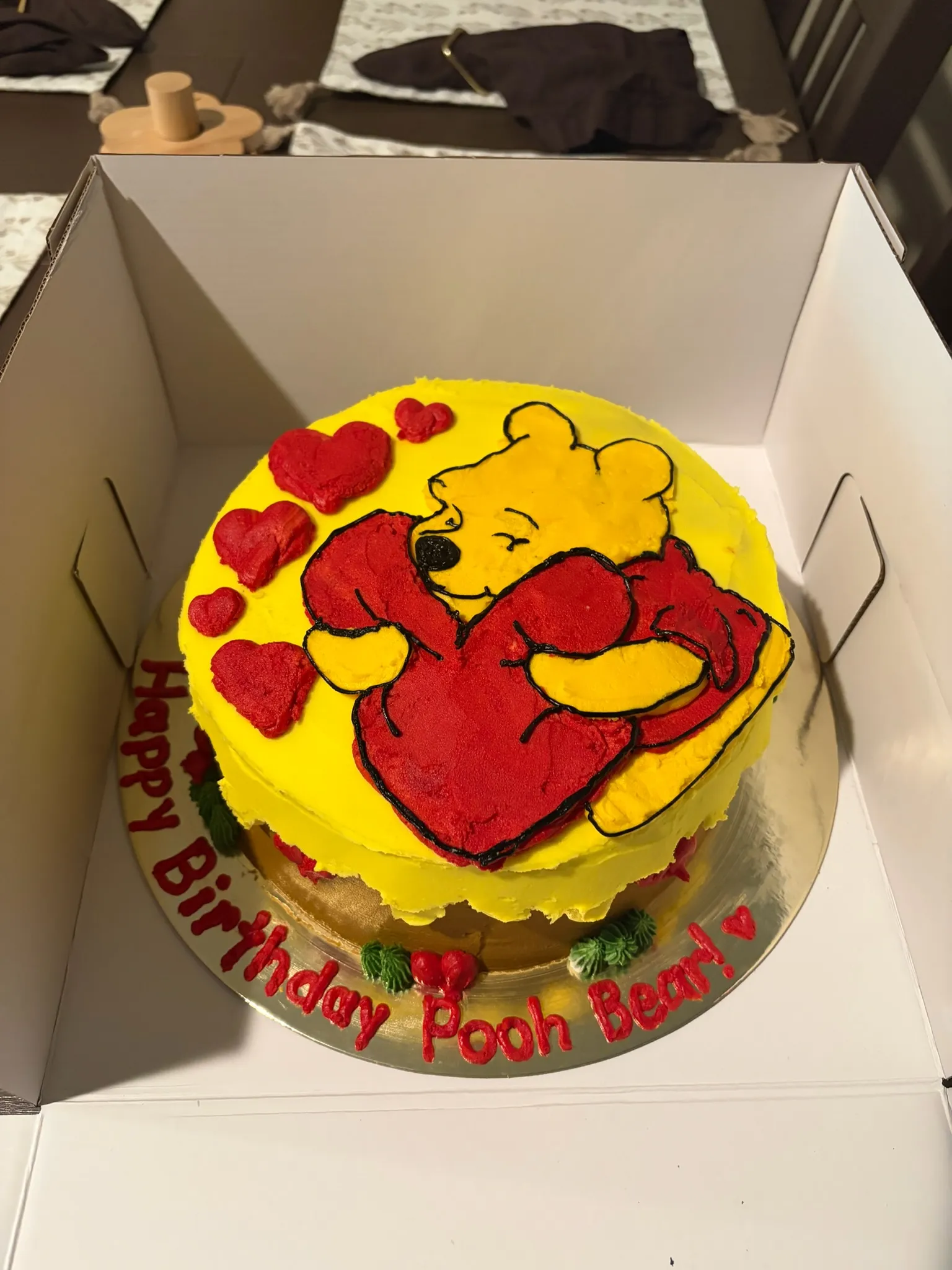 A yellow cake hand-piped with a Winnie the Pooh design
