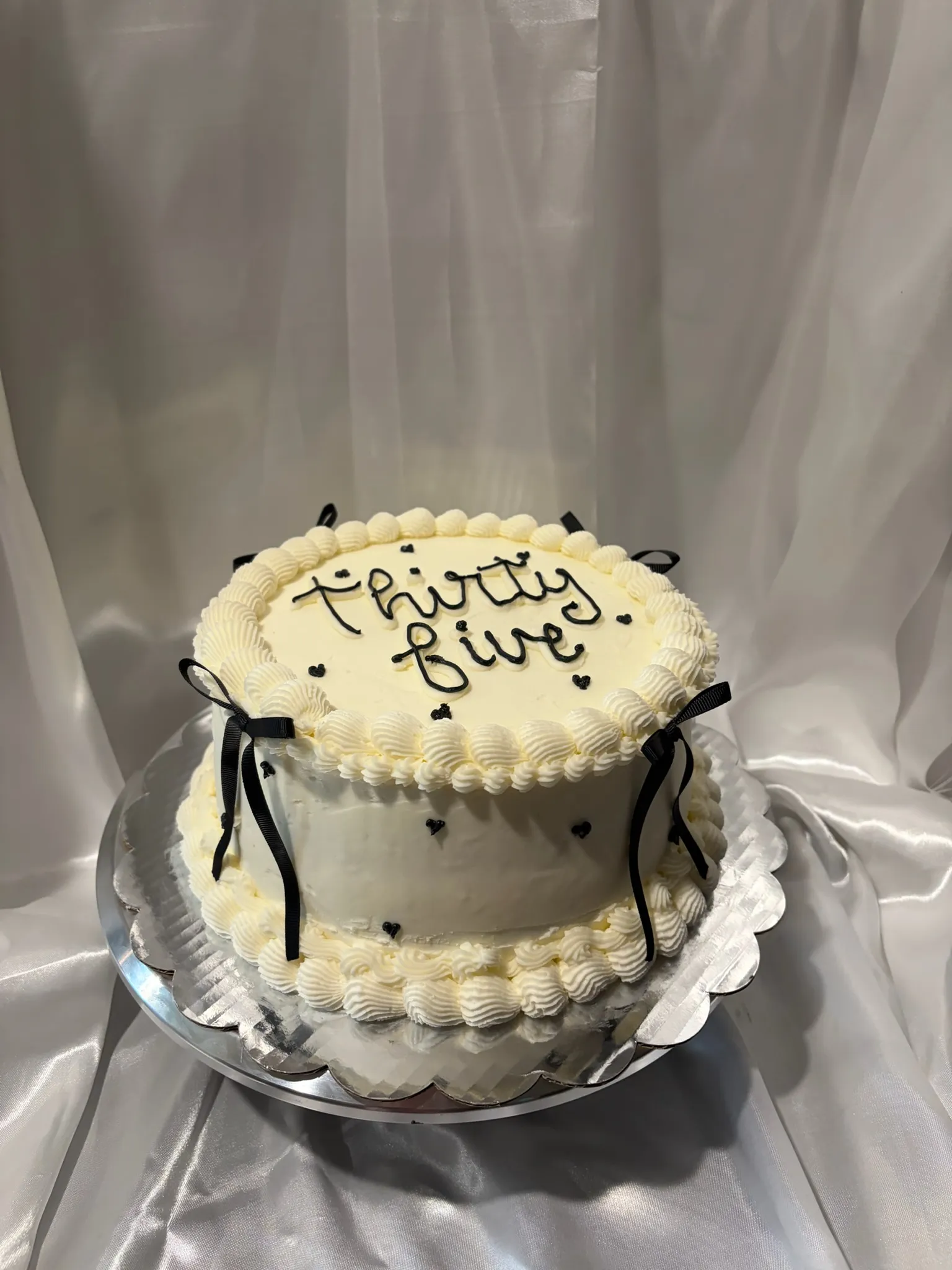 A smooth white celebration cake finished with a satin bow