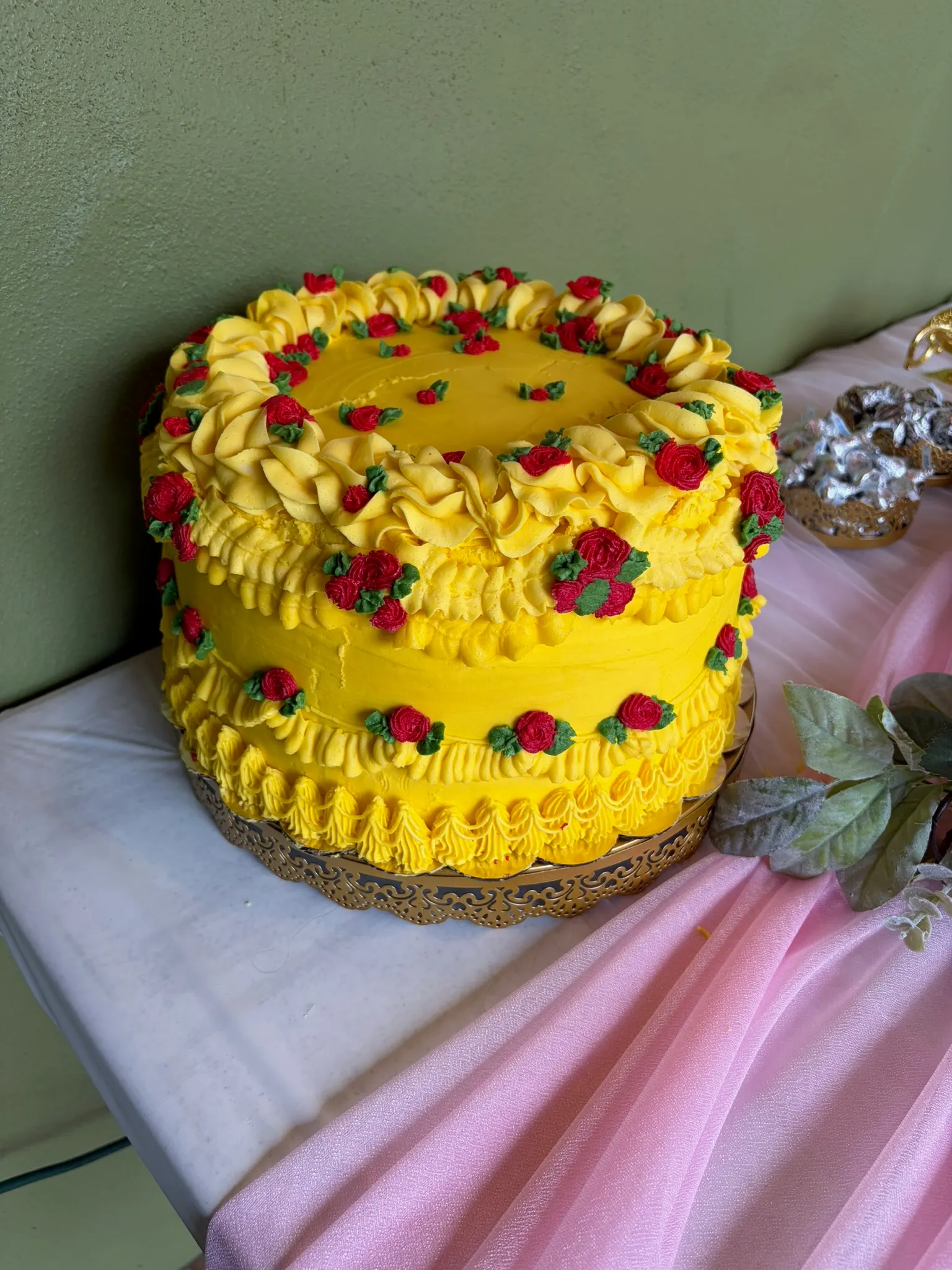 A yellow buttercream cake piped with berries and shell borders