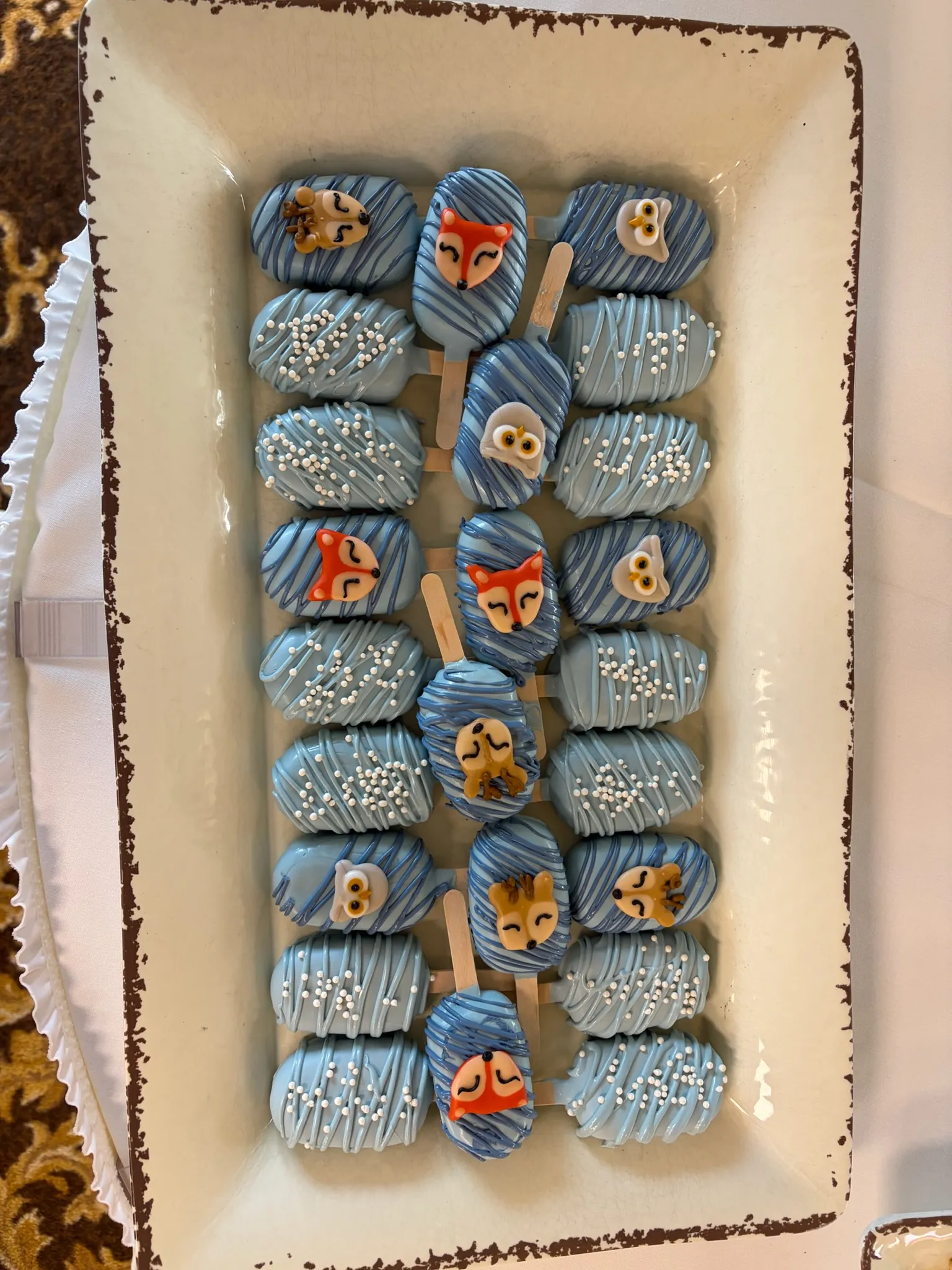 Blue-drizzled cake pops lined up on a tray