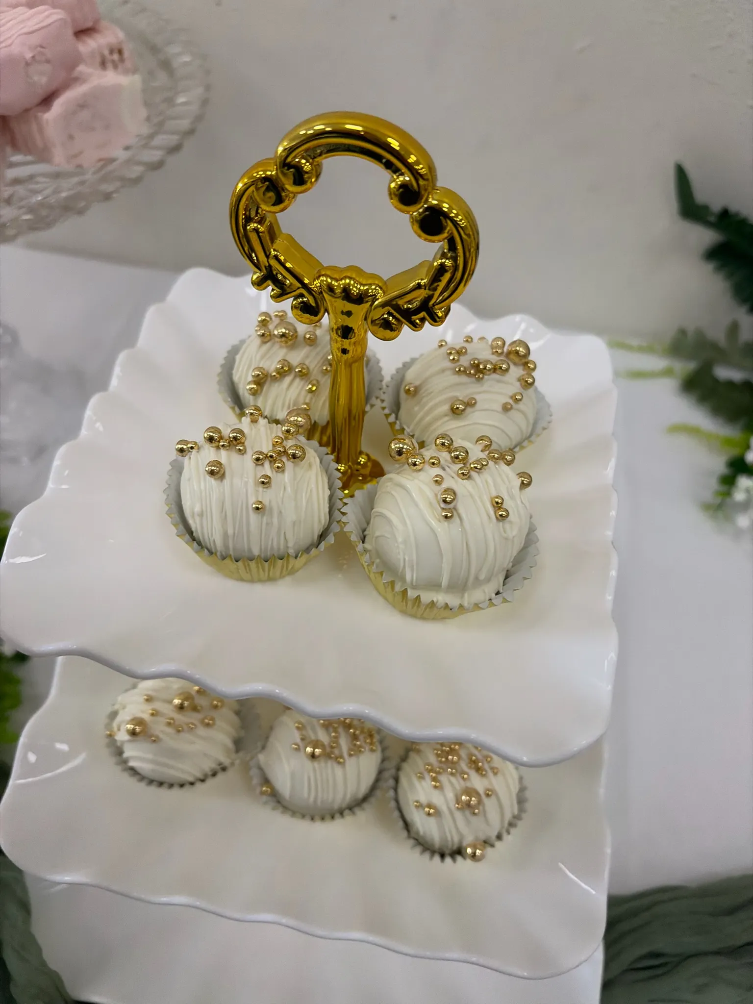 Gold and pearl cake pops served on a white stand