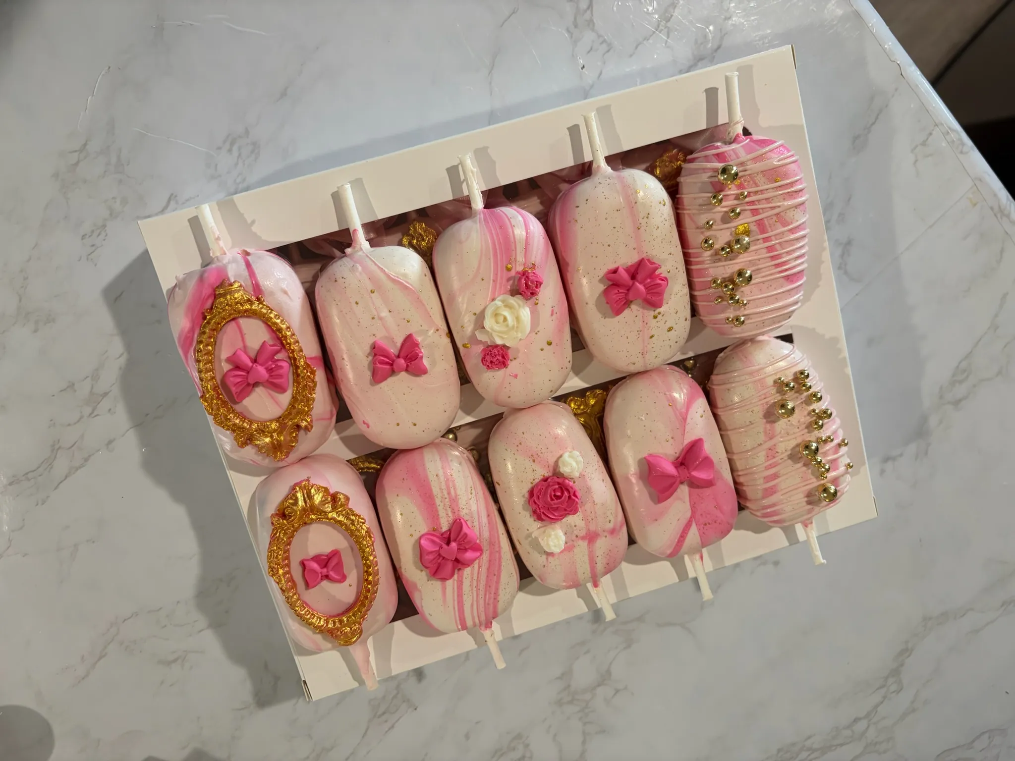 Pink cake pops decorated with bows and gold cameo details