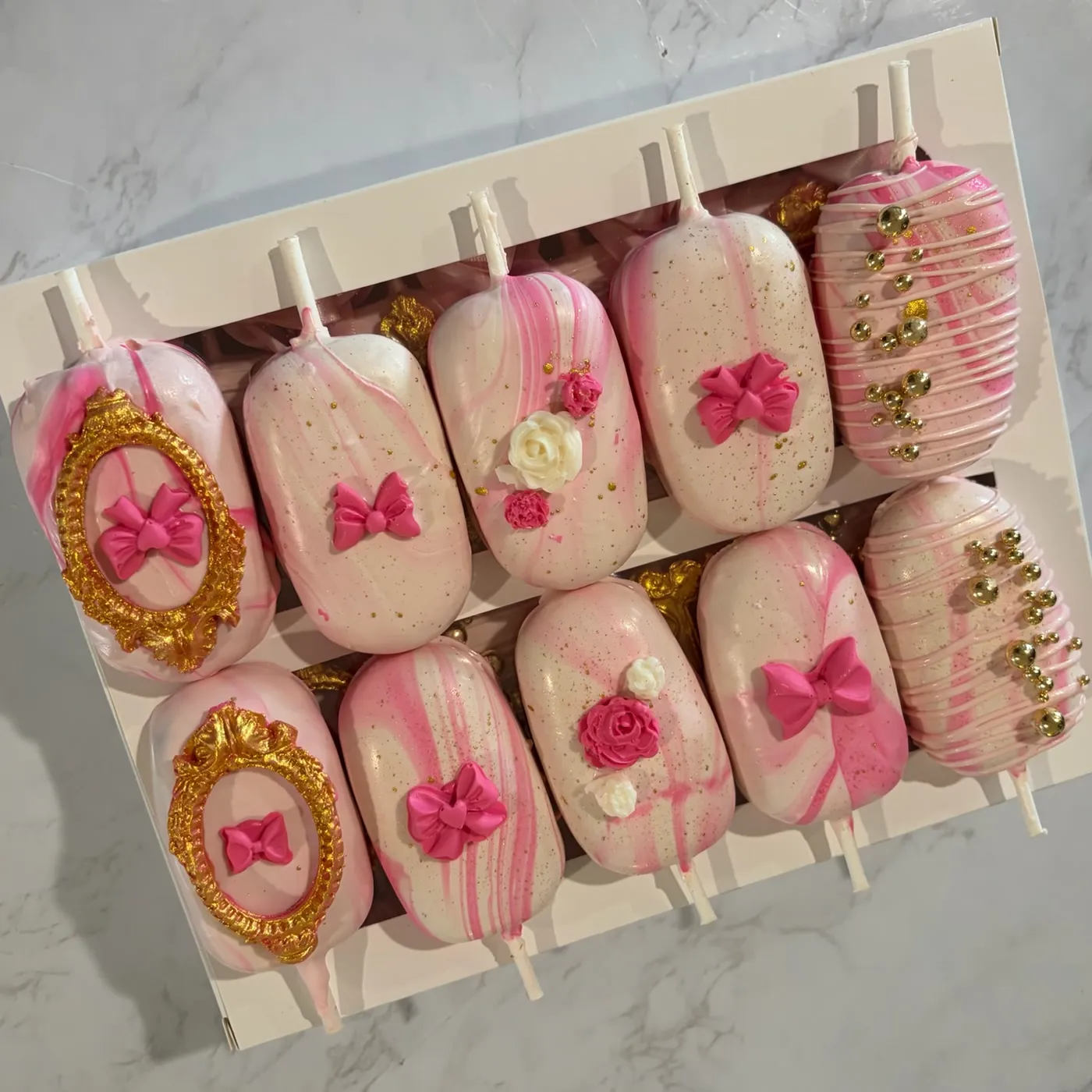 Pink cake pops decorated with bows and gold cameo details