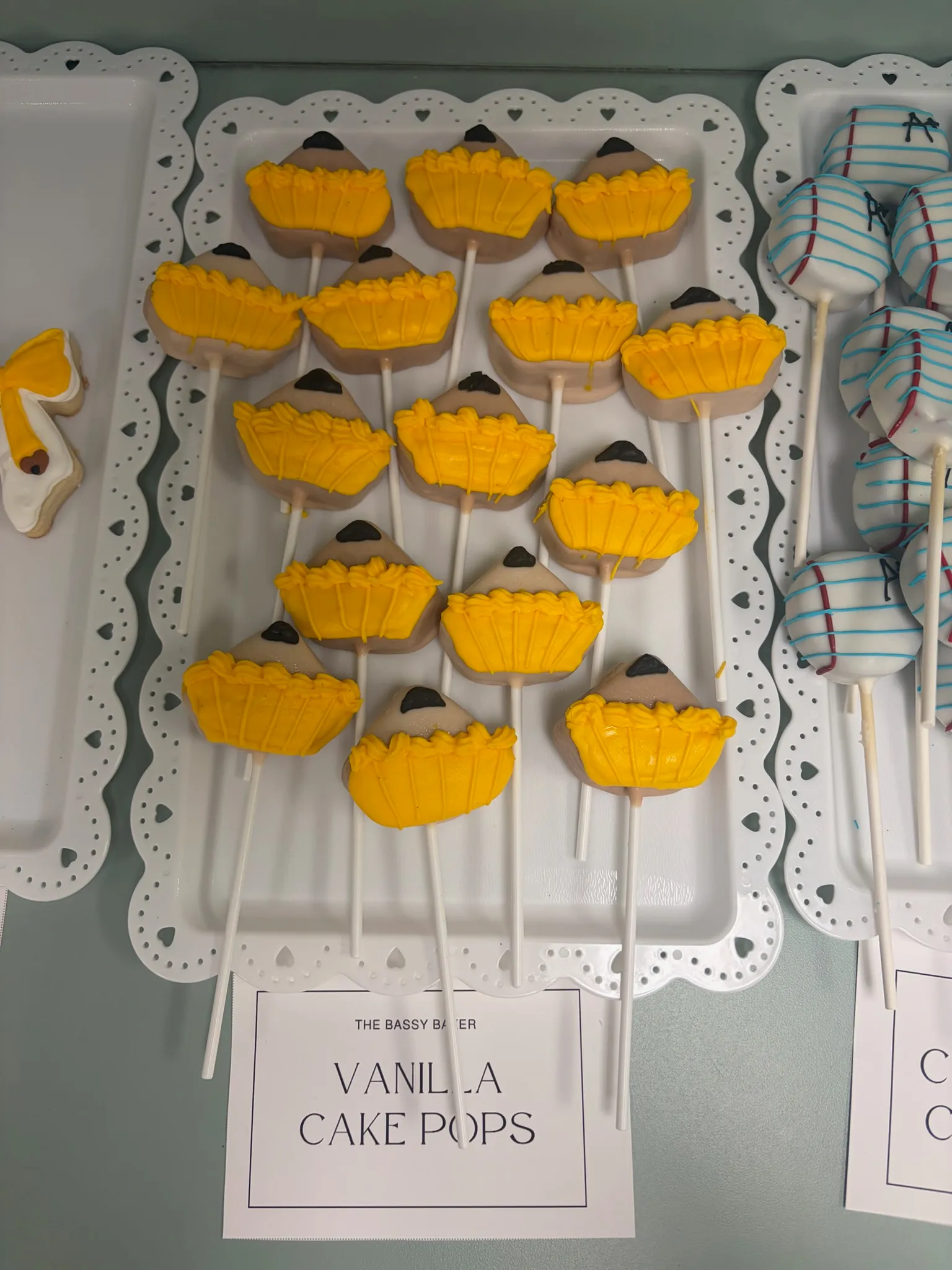 Yellow cake pops arranged on a labelled tray