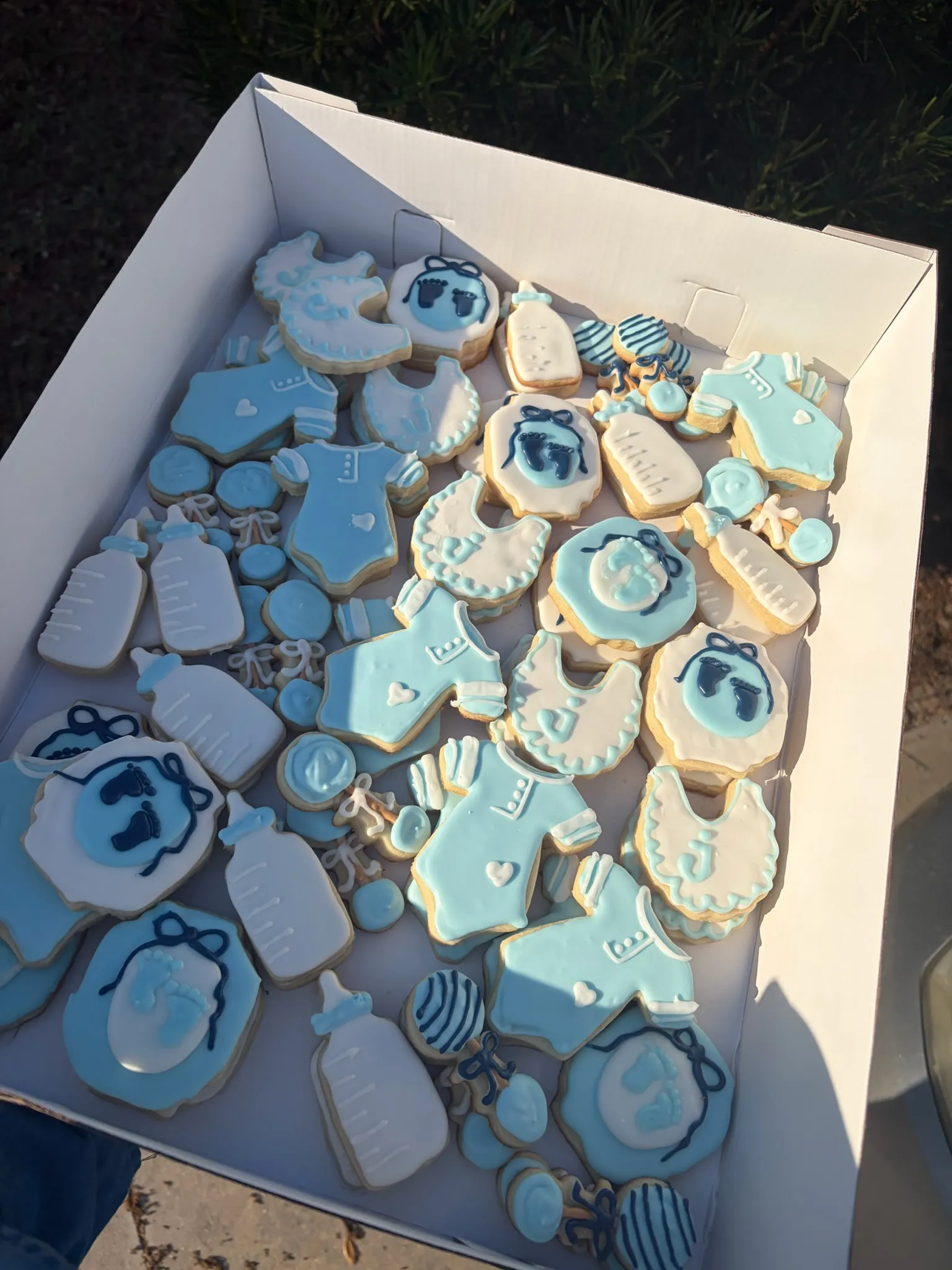 Blue baby shower cookies including bottles, bibs and rattles