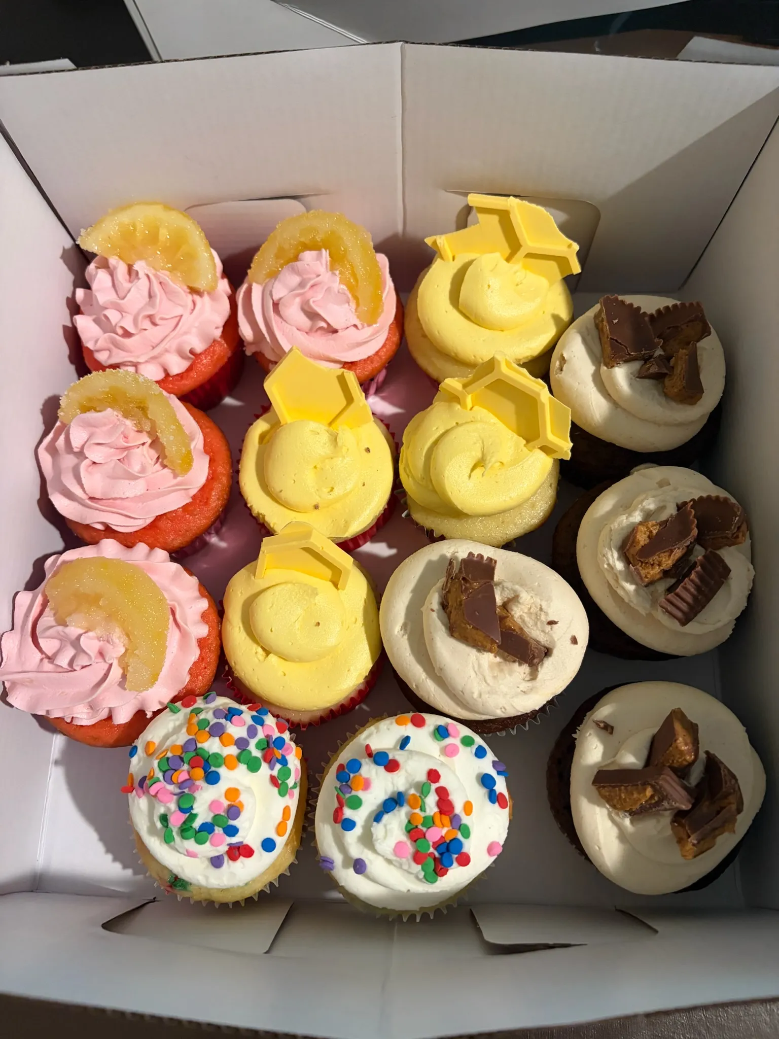 A box of assorted cupcakes with swirled frosting