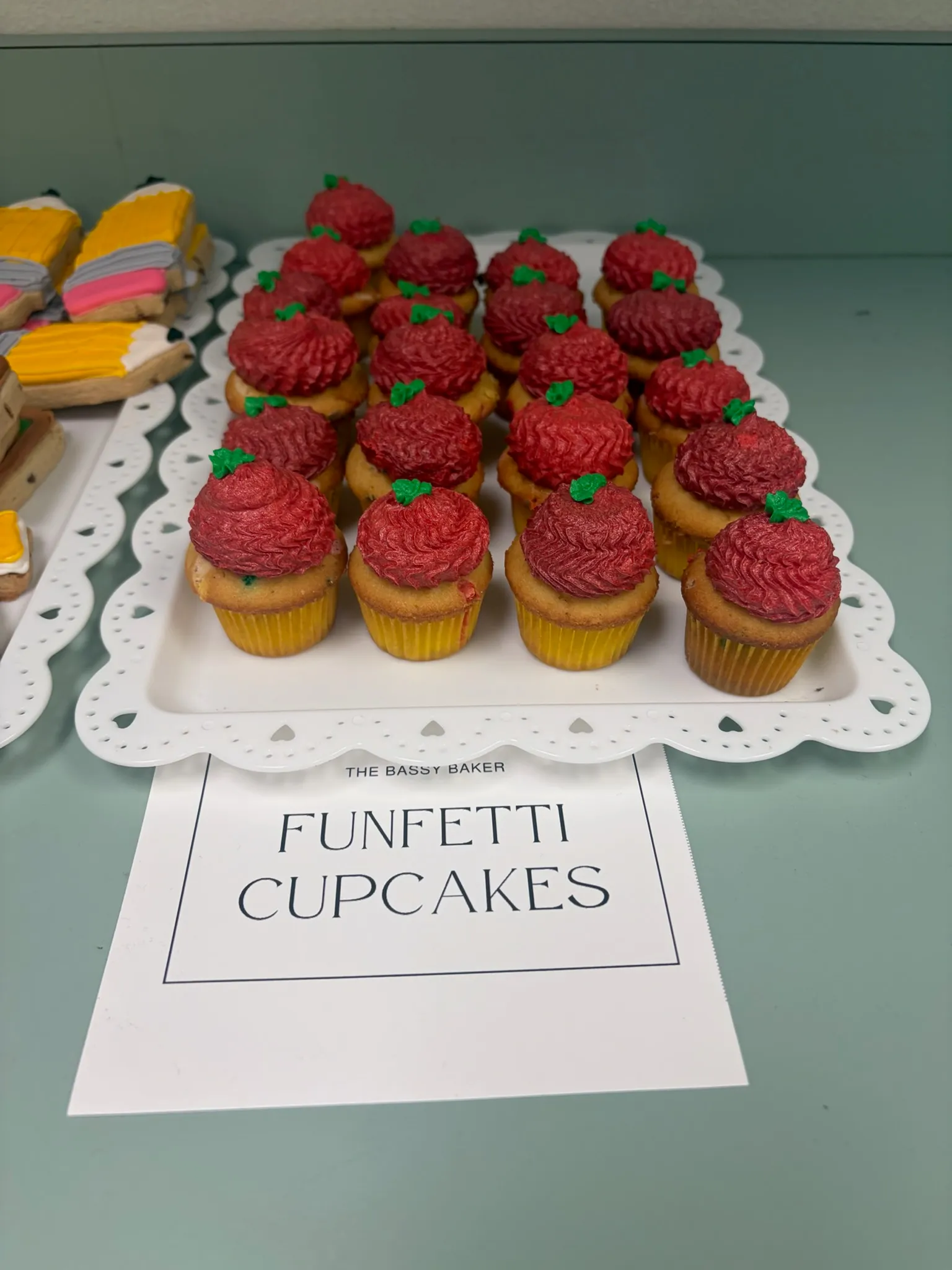A tray of funfetti cupcakes topped with red buttercream swirls