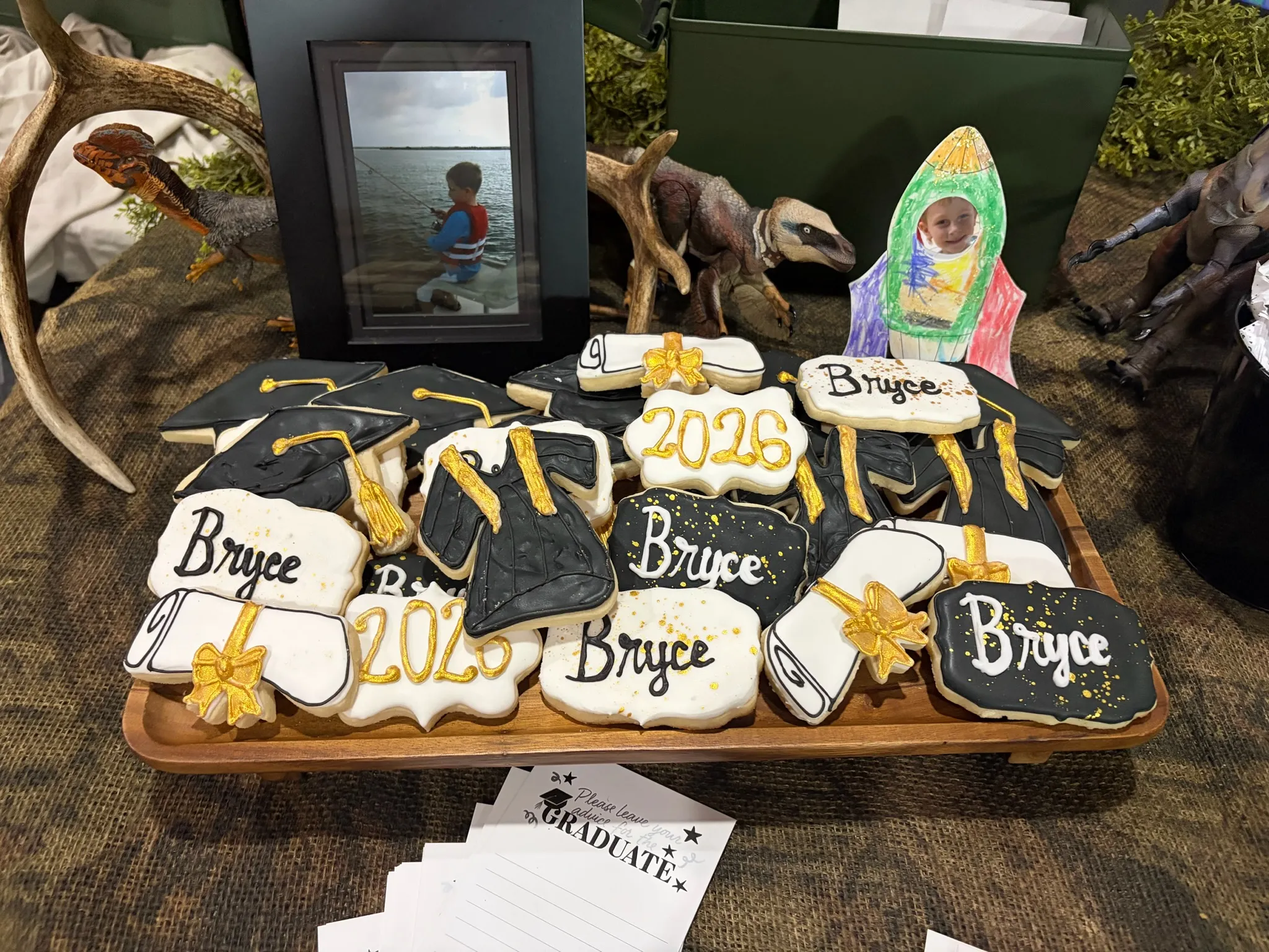 A graduation dessert table with named cookies and a photo display