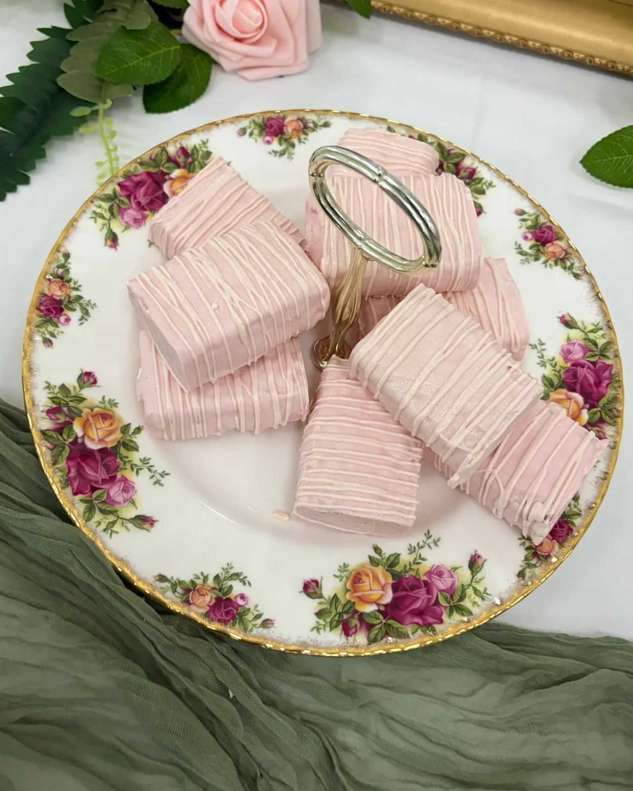Pink-dipped treats drizzled with white chocolate on a floral plate